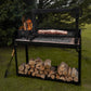 Meat cooking on the Asaparri Santa Maria grill outdoors, with a fire in the side brasero and logs below the base.